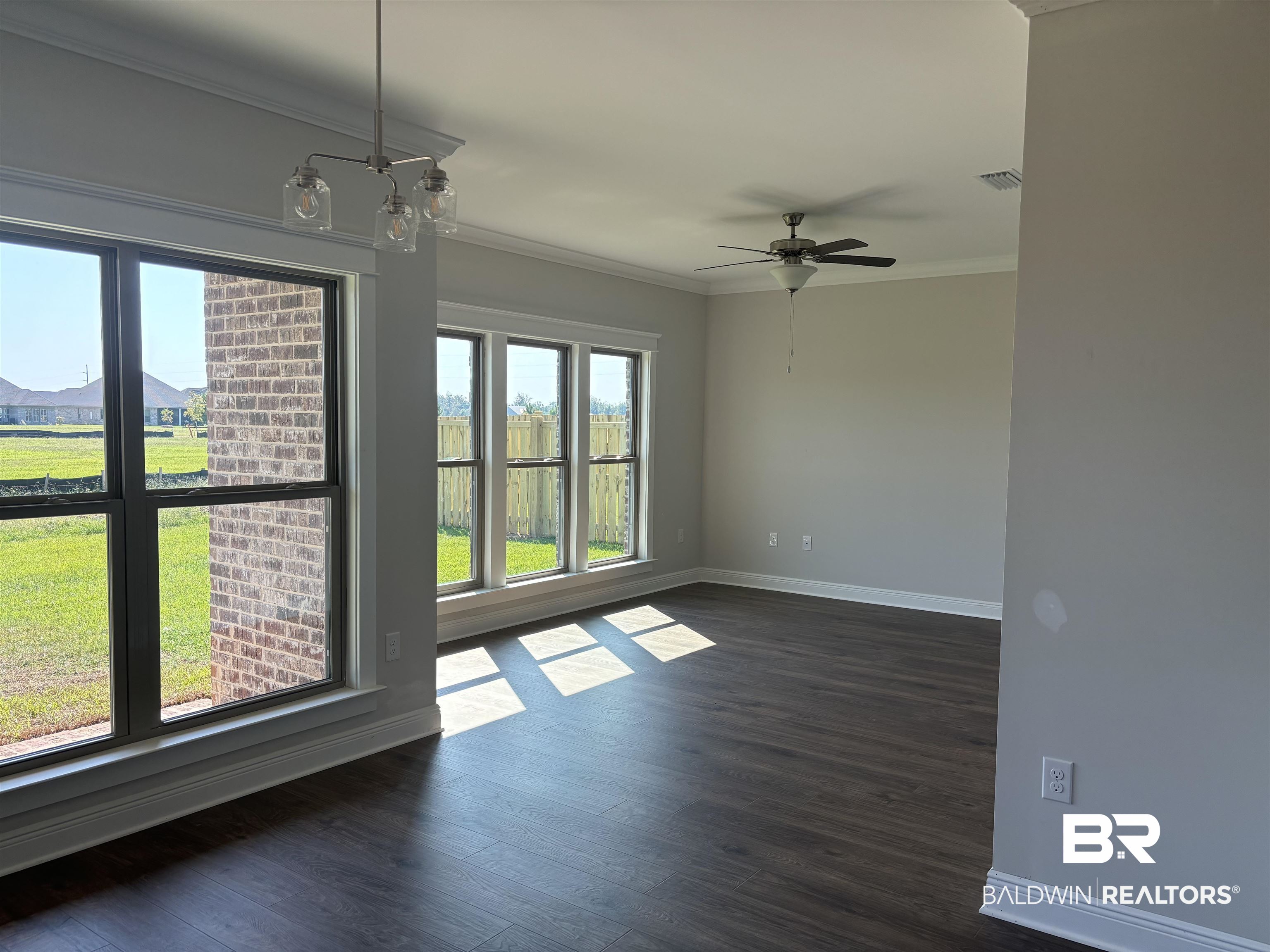 388 Garrison Boulevard Fairhope, AL 36532 - Photo 9 of 34 Unfurnished room with ceiling fan with notable chandelier, dark hardwood / wood-style flooring, and ornamental molding