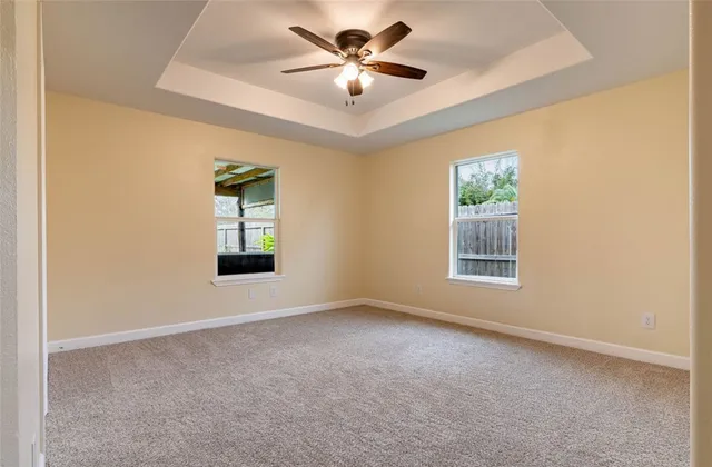 an empty room with windows and ceiling fan