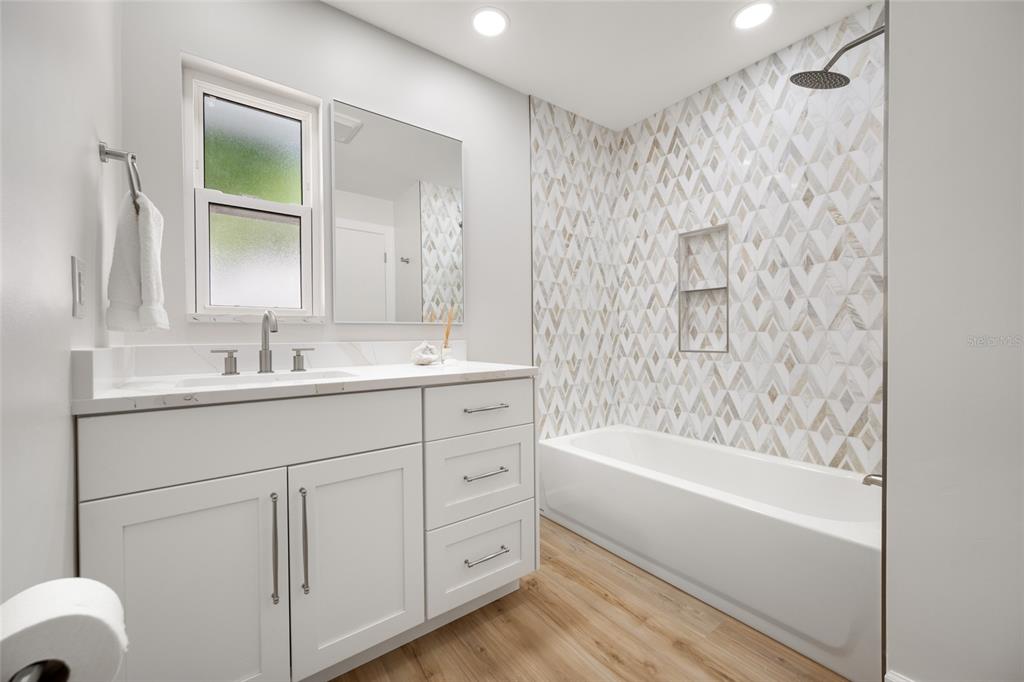 656 Mehlenbacher Road Belleair, FL 33756 - Photo 34 of 49 a bathroom with a bathtub a sink a vanity and a shower