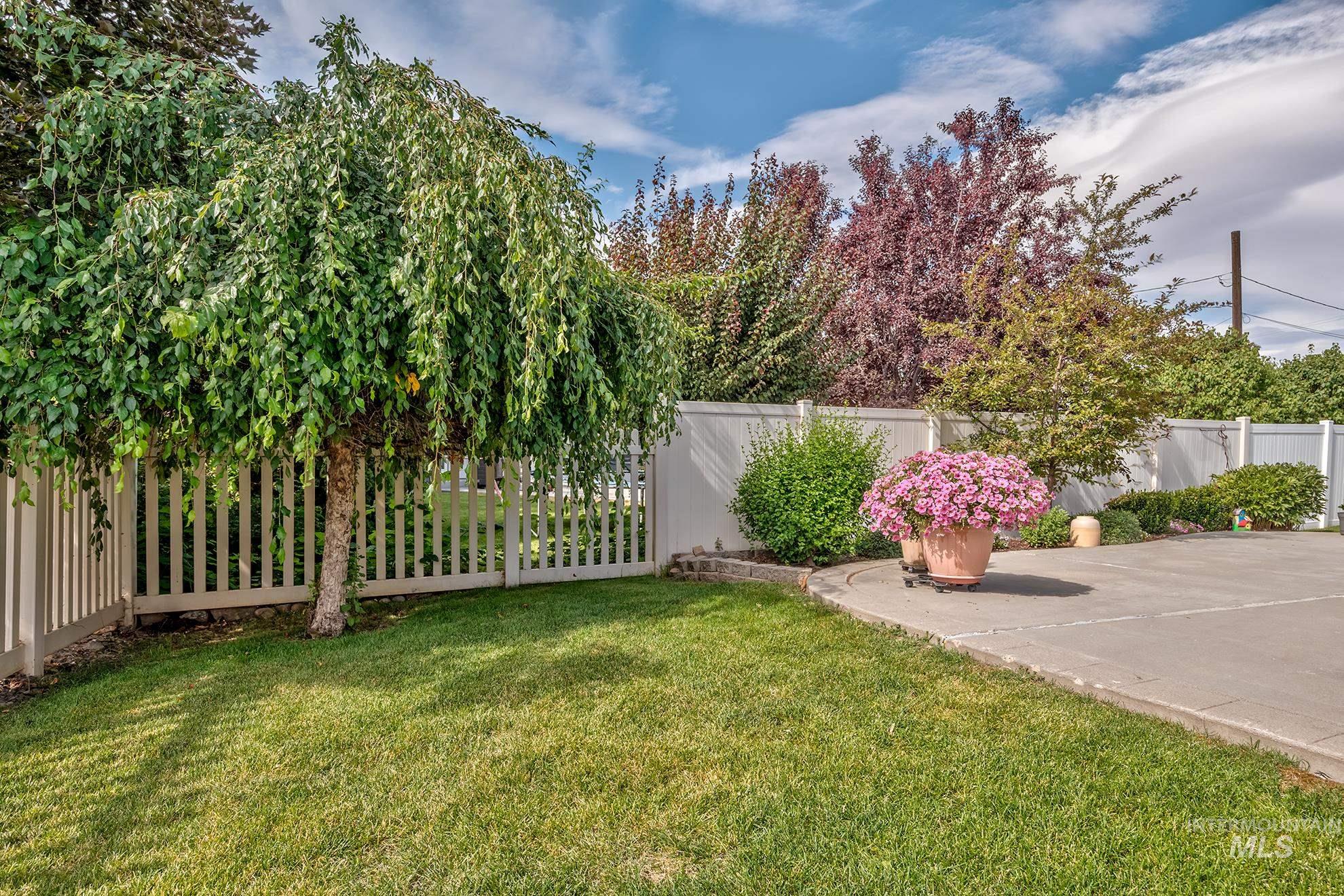 420 West Indianhead Road Weiser, ID 83672 - Photo 36 of 40 Manicured lawn area featuring a mature weeping tree, white picket fencing, and a concrete patio