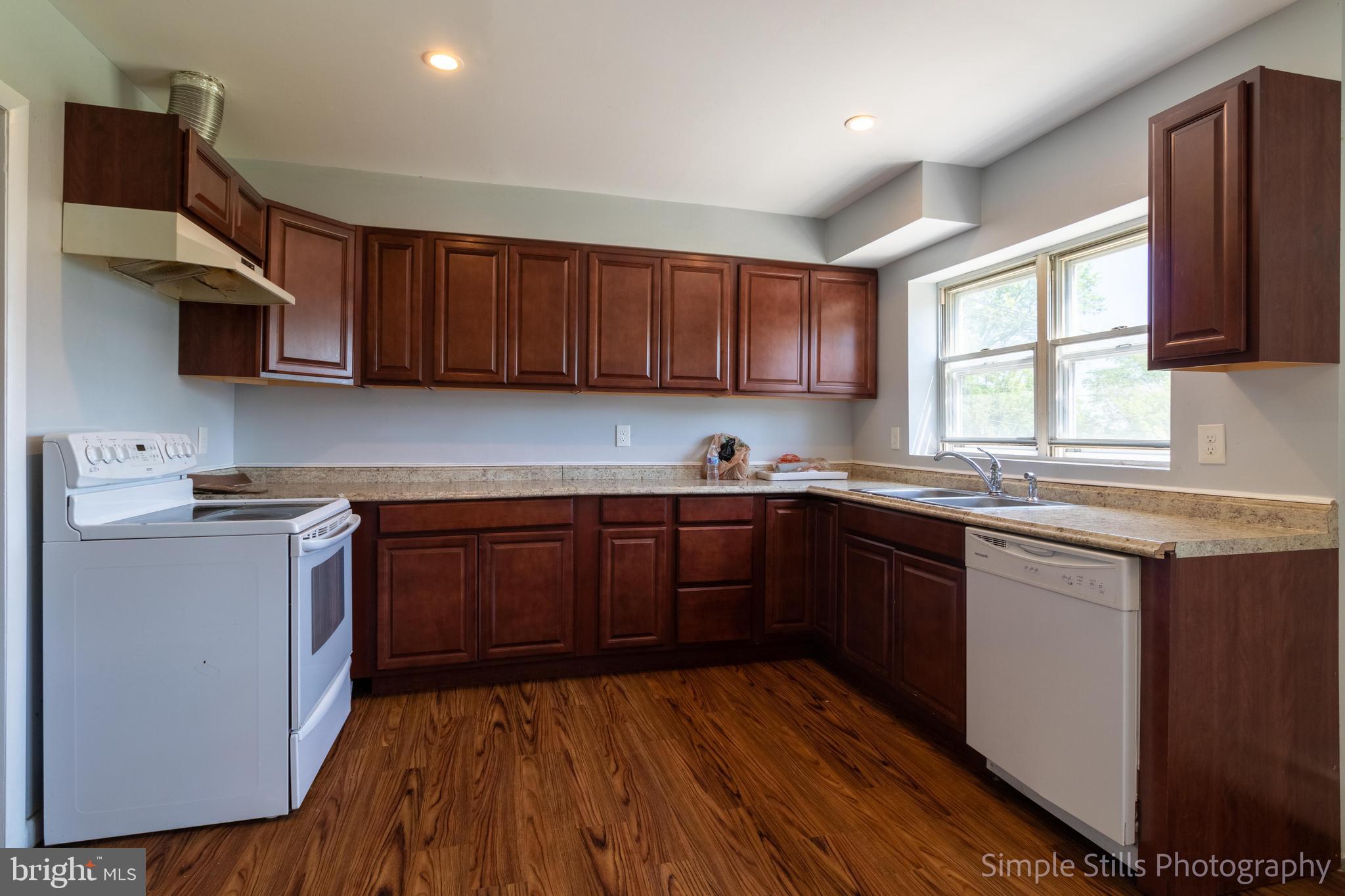a kitchen with stainless steel appliances granite countertop wooden cabinets a stove a sink and a window
