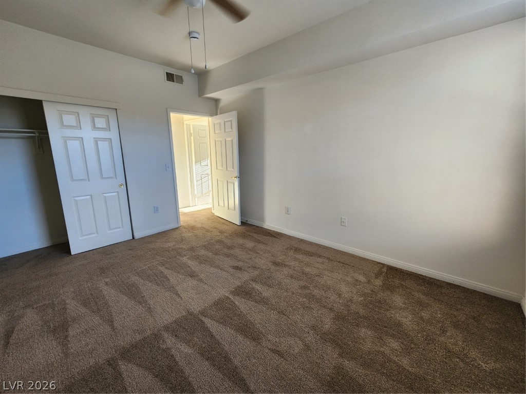 231 West Horizon Ridge Parkway, Unit 417 Henderson, NV 89012 - Photo 24 of 39 Unfurnished bedroom with dark colored carpet, a closet, and a ceiling fan