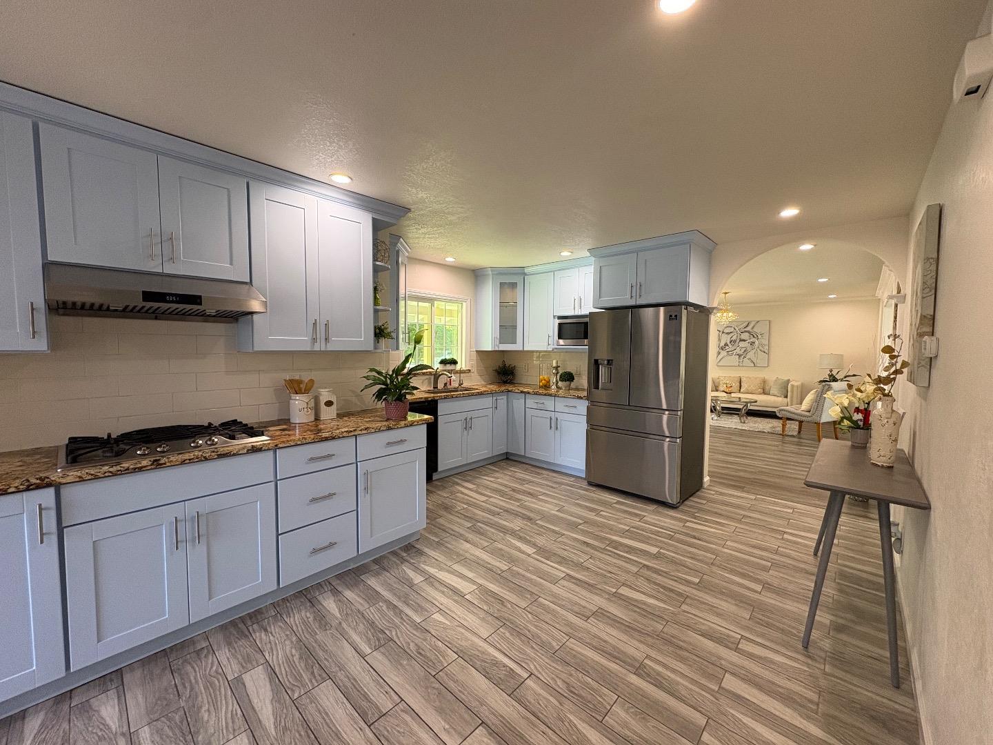 5187 Doyle Road San Jose, CA 95129 - Photo 15 of 39 a large kitchen with stainless steel appliances granite countertop a stove a sink dishwasher and a refrigerator with wooden floor