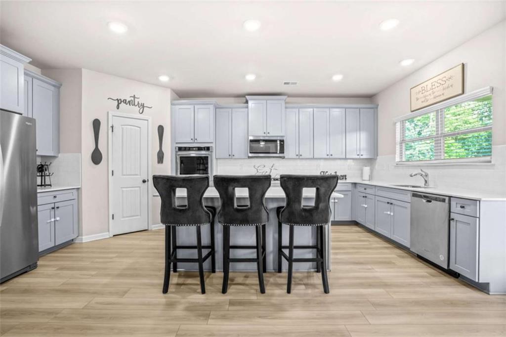 361 Traditions Lane Hampton, GA 30228 - Photo 8 of 35 a kitchen with stainless steel appliances a dining table chairs refrigerator and sink