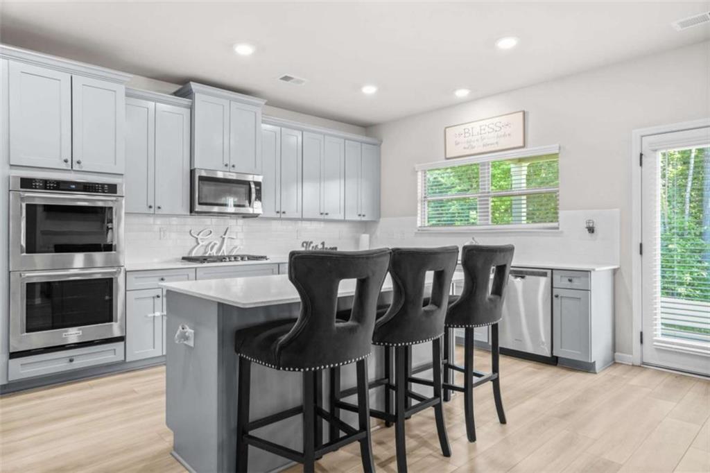 361 Traditions Lane Hampton, GA 30228 - Photo 10 of 35 a kitchen with kitchen island granite countertop a table chairs microwave and sink