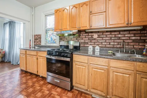 a kitchen with granite countertop a stove a sink and white cabinets