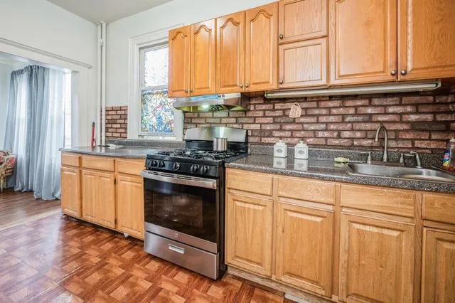 a kitchen with granite countertop a stove a sink and white cabinets