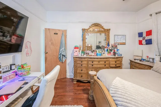 a bedroom with a bed and a flat tv screen on dresser