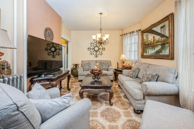 a living room with furniture a flat screen tv and a chandelier