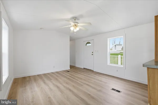 a view of empty room with wooden floor and fan