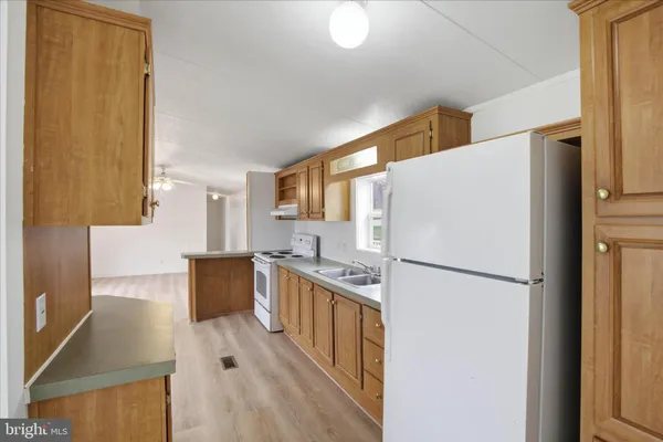 a kitchen with stainless steel appliances a refrigerator a stove a sink dishwasher and white countertops with wooden floor