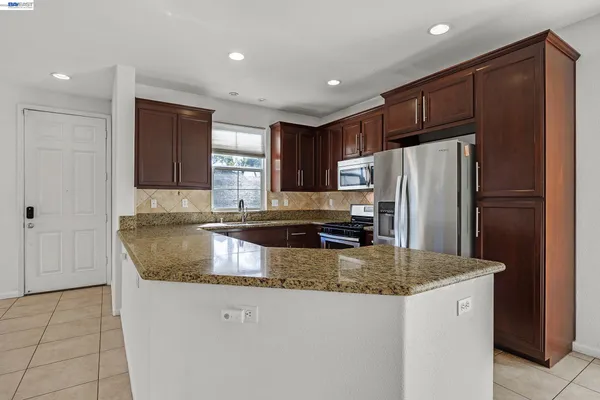 a kitchen with stainless steel appliances granite countertop a refrigerator a sink and a stove