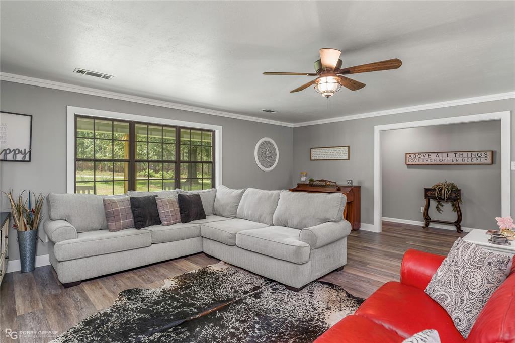 1426 Caney Lake Road Minden, LA 71055 - Photo 2 of 36 Spacious living area featuring wood-finish flooring, a ceiling fan with integrated lighting, and crown molding