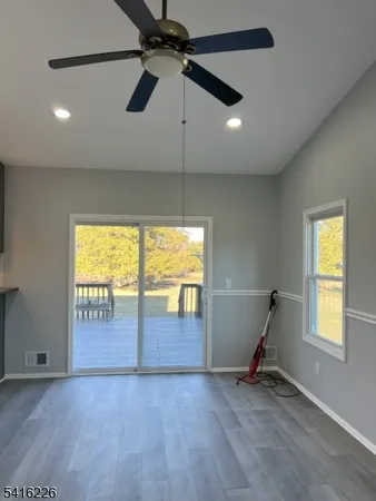 an empty room with windows and chandelier fan