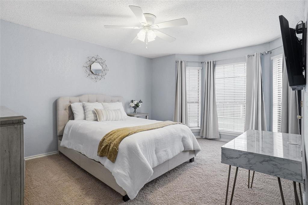 2613 Stone Hollow Drive Bedford, TX 76021 - Photo 17 of 33 a bedroom with a bed a chandelier and a flat tv screen on dresser