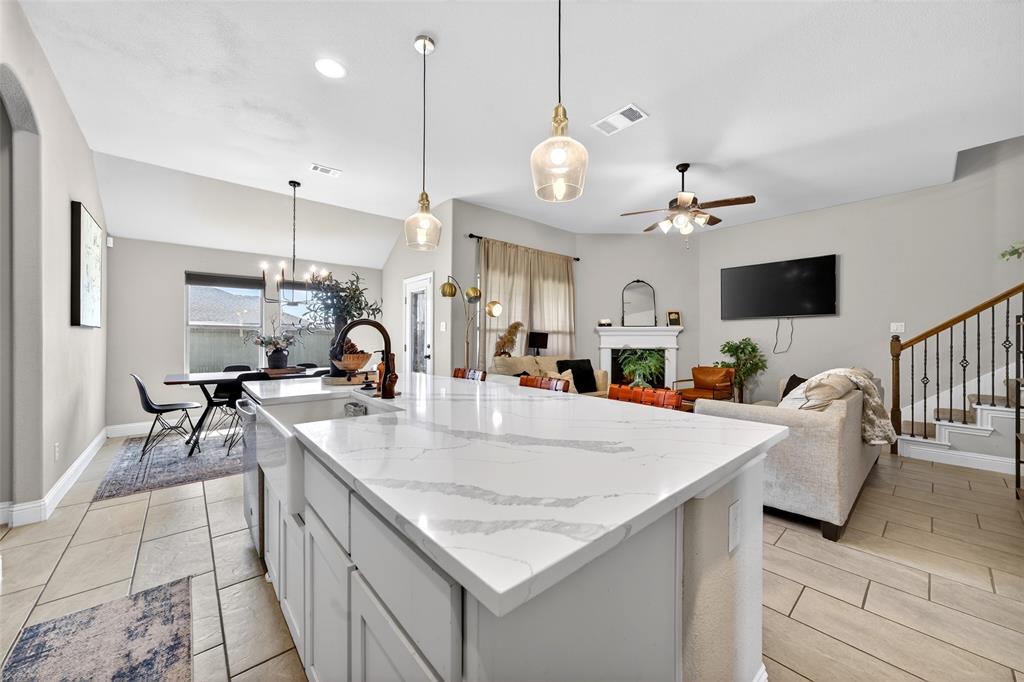 3245 Ribisl Lane Royse City, TX 75189 - Photo 39 of 39 Kitchen featuring light stone countertops, open floor plan, a center island with sink, a ceiling fan, and white cabinetry
