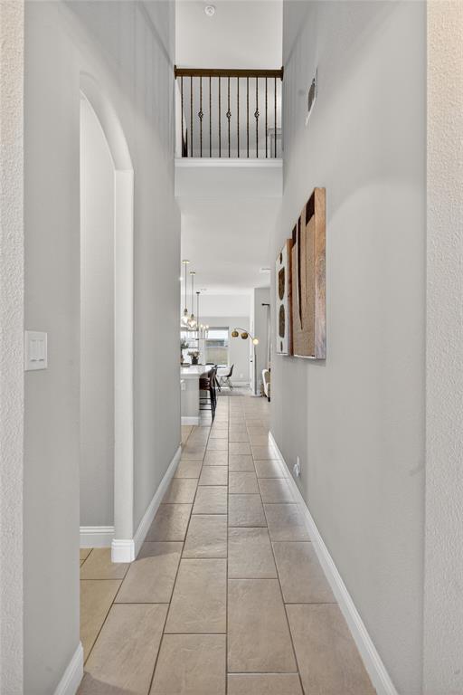 3245 Ribisl Lane Royse City, TX 75189 - Photo 15 of 39 Hallway featuring light tile patterned floors, a high ceiling, and arched walkways