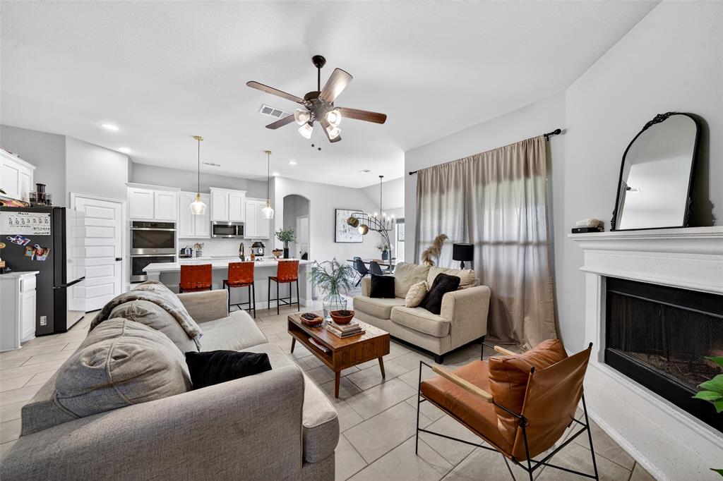 3245 Ribisl Lane Royse City, TX 75189 - Photo 7 of 39 Living area featuring ceiling fan, a fireplace, arched walkways, and a chandelier