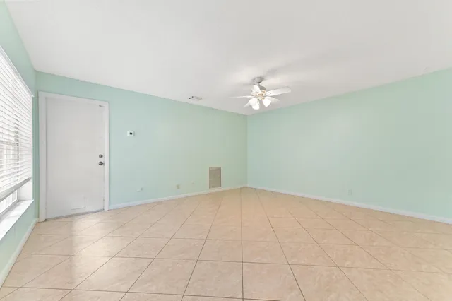 a view of an empty room with window and chandelier fan