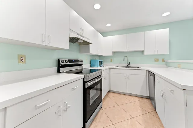 a kitchen with a sink dishwasher and white cabinets with wooden floor