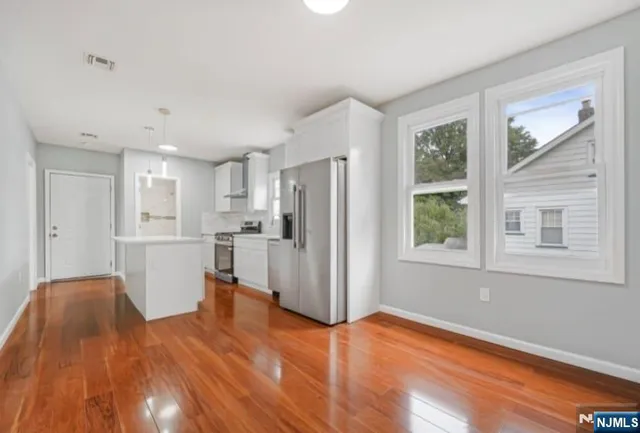 a view of open kitchen with wooden floor and refrigerator