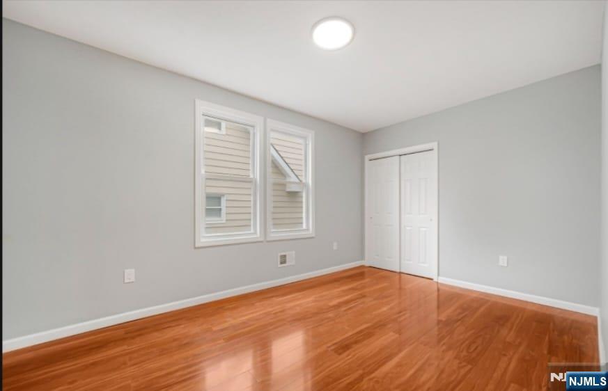 125 Birch Street, Unit 2 Bloomfield, NJ 07003 - Photo 7 of 11 an empty room with wooden floor and windows