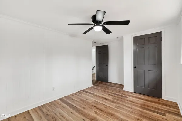 an empty room with wooden floor and a ceiling fan