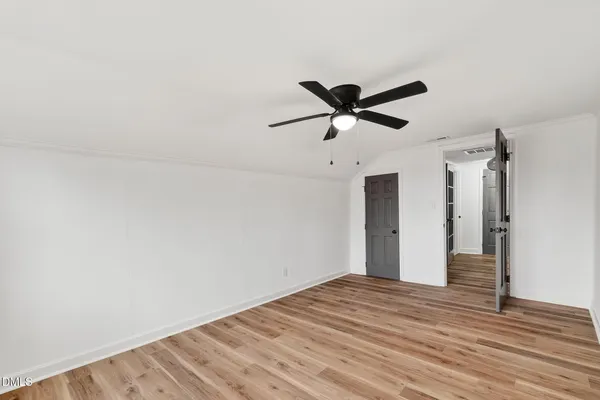 a view of a room with wooden floor and a ceiling fan
