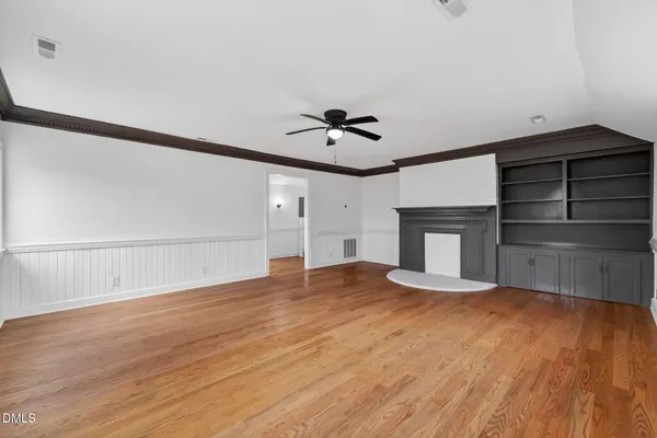 a view of an empty room with a window and wooden floor