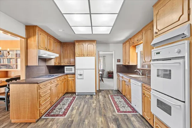 a kitchen with stainless steel appliances granite countertop a refrigerator a stove a sink dishwasher and wooden cabinets with wooden floor