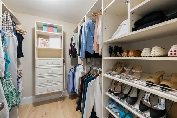 a view of walk in closet with clothes and shoes