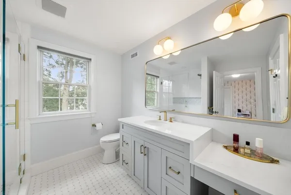 a spacious bathroom with a double vanity sink toilet and a mirror