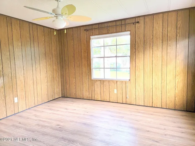 an empty room with wooden floor closet and windows