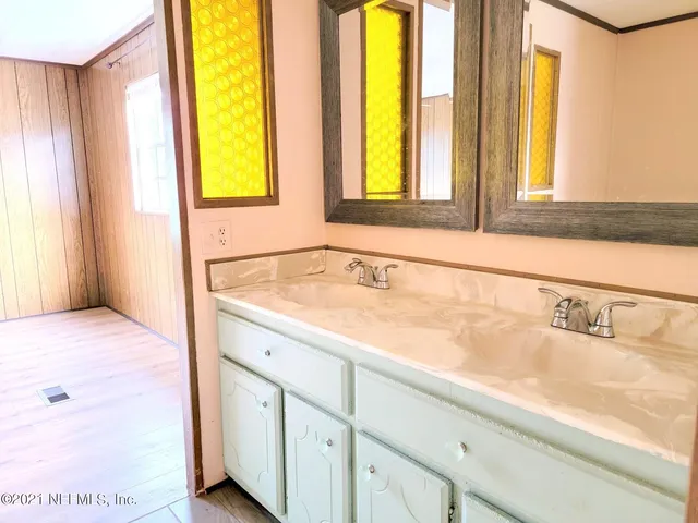 a bathroom with a granite countertop sink and a large mirror next to a window