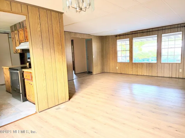 a view of a livingroom with wooden floor and a refrigerator