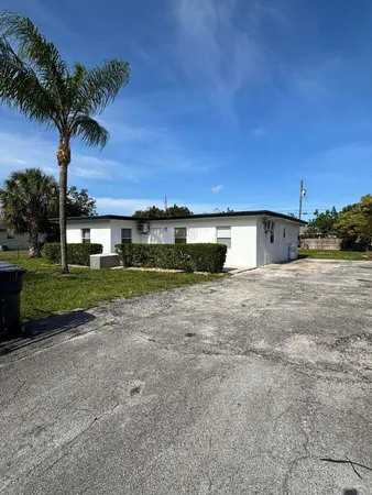 a front view of a house with a yard and palm trees