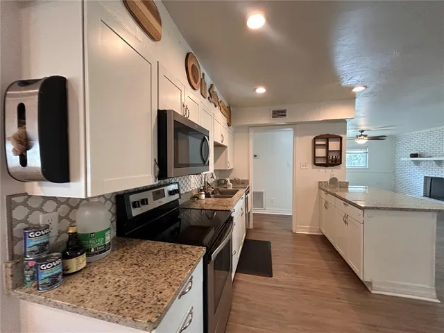 a kitchen with stainless steel appliances granite countertop a stove top oven a sink a counter space and cabinets