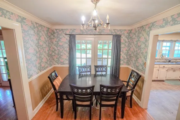 a kitchen with a refrigerator a stove a sink and a dining table with wooden floor