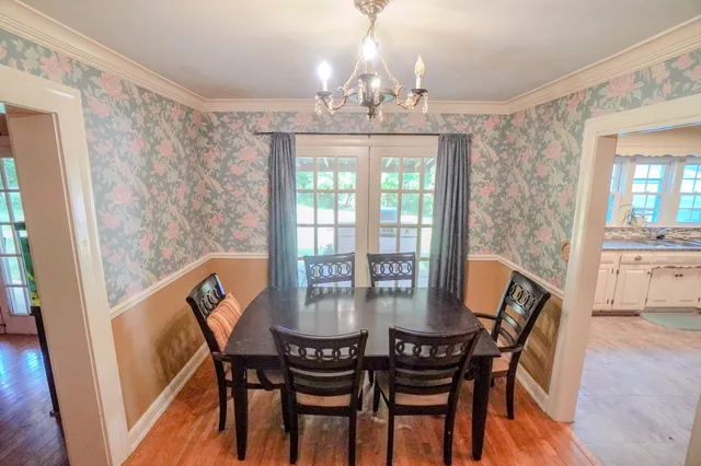 a kitchen with a refrigerator a stove a sink and a dining table with wooden floor