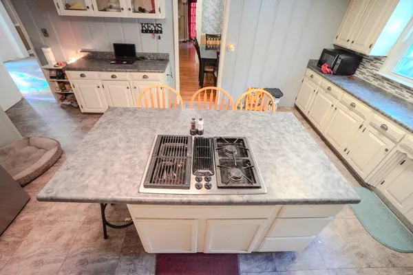 a kitchen with stainless steel appliances kitchen island granite countertop a stove a sink a dining table and chairs with wooden floor