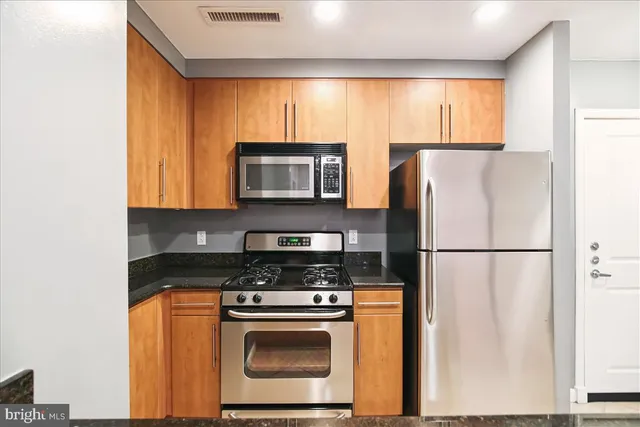 a view of kitchen with stainless steel appliances granite countertop a refrigerator and a sink