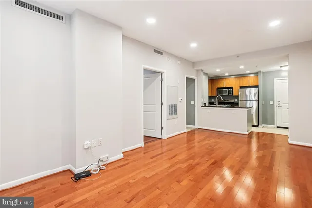 a view of an empty room with wooden floor and a window