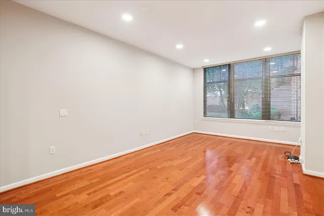an empty room with wooden floor and kitchen view