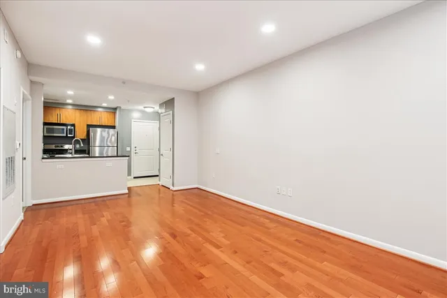 a view of an empty room with wooden floor and a window