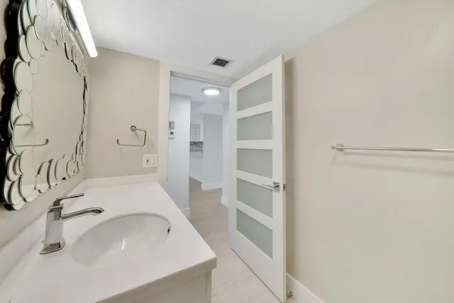 a bathroom with a sink and mirror with bathtub