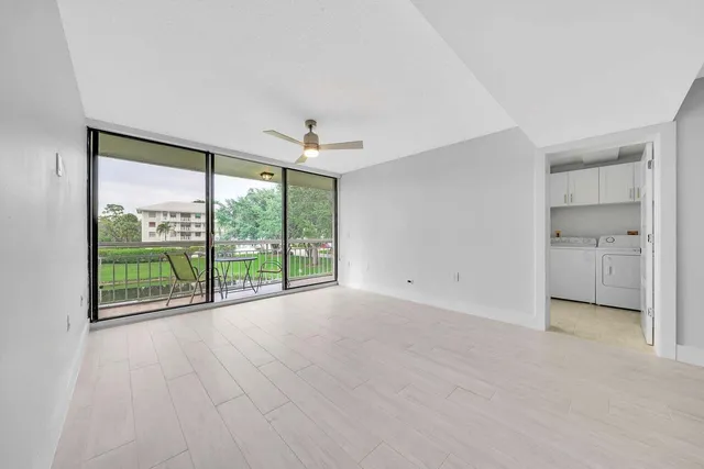 a view of an empty room with a window and a kitchen view