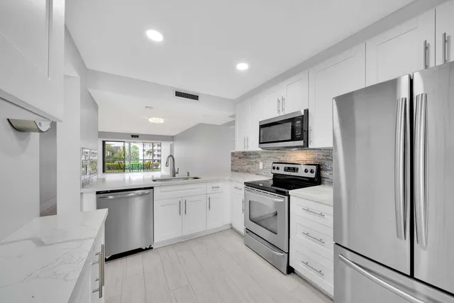 a kitchen with granite countertop a sink stainless steel appliances and white cabinets
