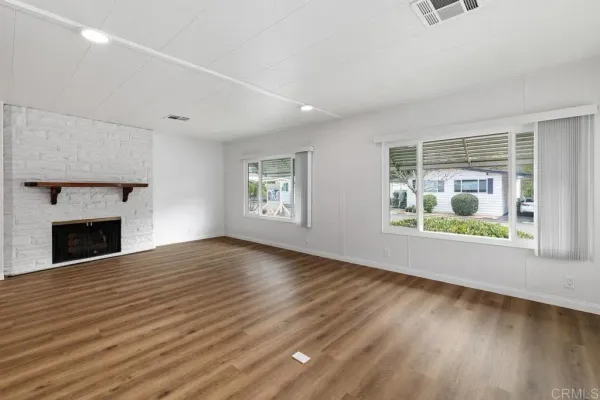 an empty room with windows and fireplace