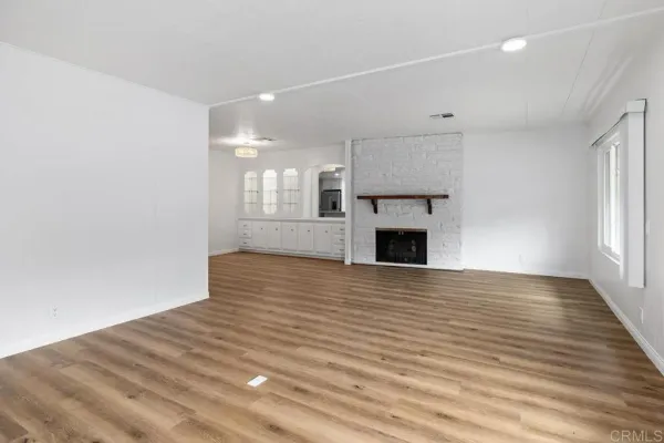 an empty room with wooden floor and a fireplace