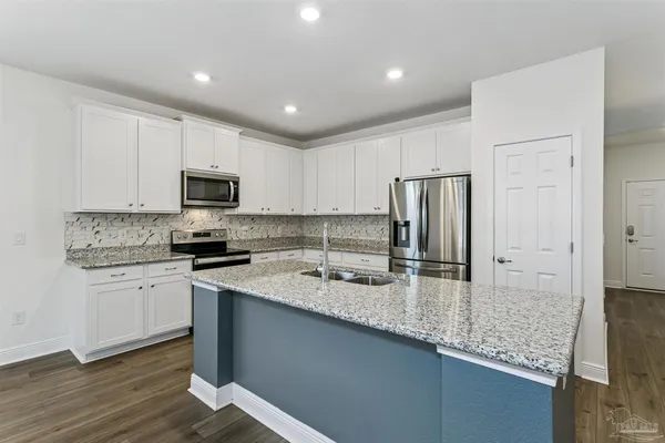 a kitchen with granite countertop a sink stove and refrigerator